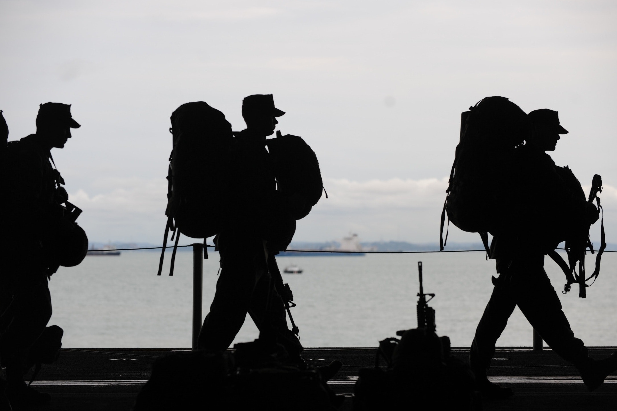 Silhouetted soldiers departing with gear